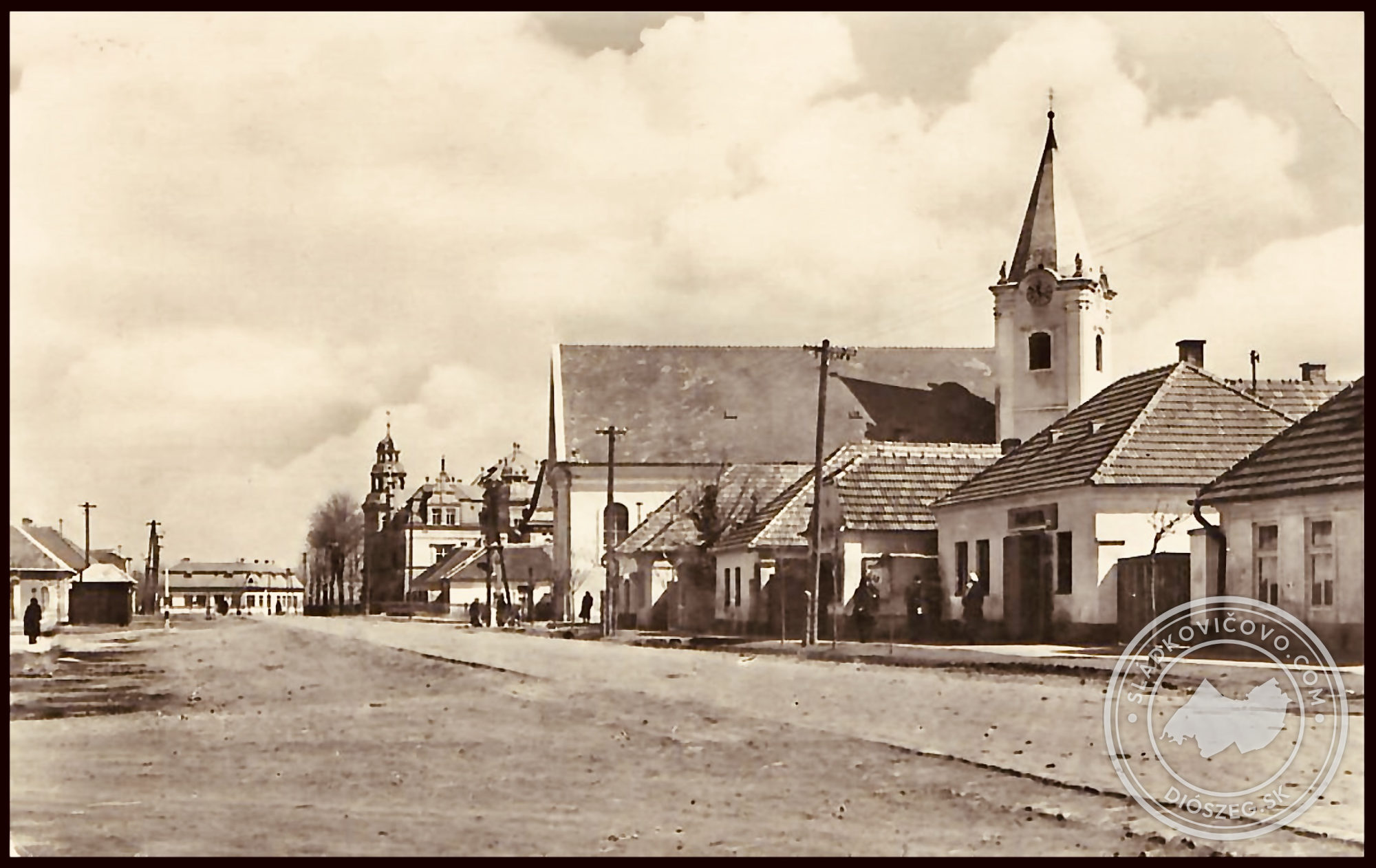 A 20. század ötvenes éveiből származó fényképen a főtér még burkolatlan felülettel látható, a r. k. templommal, a háttérben a kastéllyal és a Városi Hivatal (akkor HNB) épületével, balra pedig az egykori trafik.